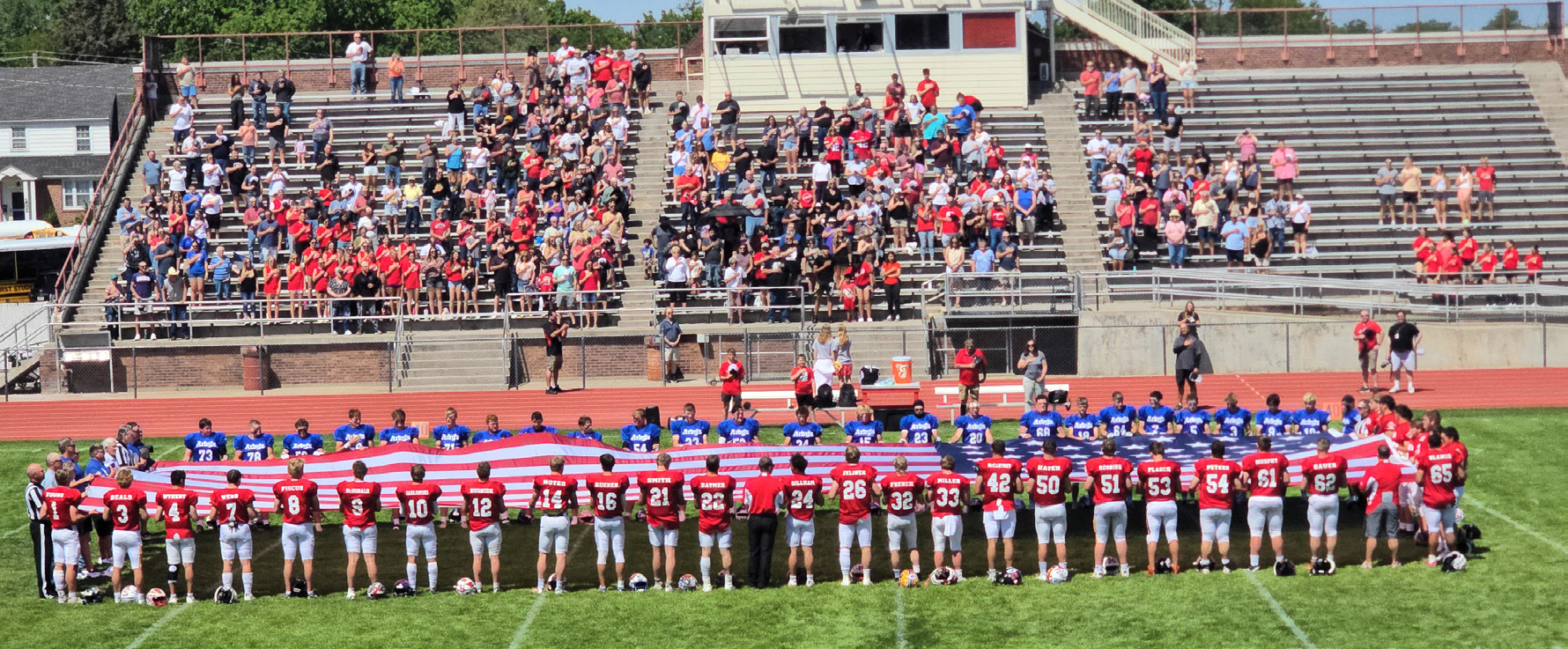 The West and East teams held the flag during the national anthem prior to kickoff of their All-Star Game. Mullen’s Justin French is #32 with his back to the camera in the middle right of the photo. Larry French is also in the photo, fourth from the top left of the flag. Christie Jones