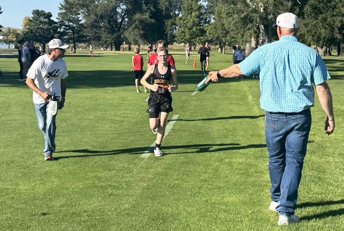 Cross country dads Travis Hampton (left) and Bryan Miller help keep Oakes Miller cool during the Ogallala race last week. Tami Miller