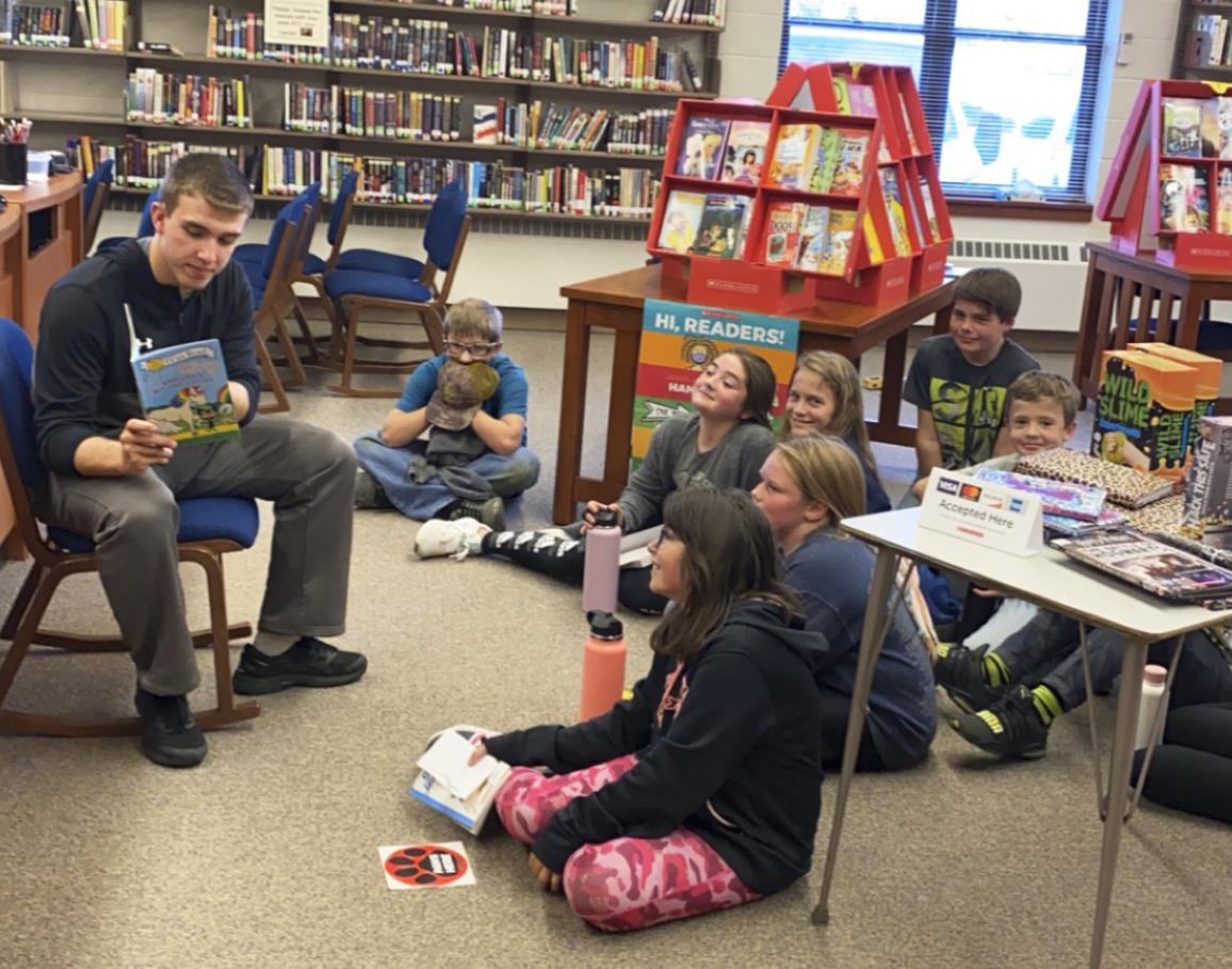 Senior Brendon Walker reads to the fifth graders during the Scholastic Book Fair in the high school library last month. courtesy photo