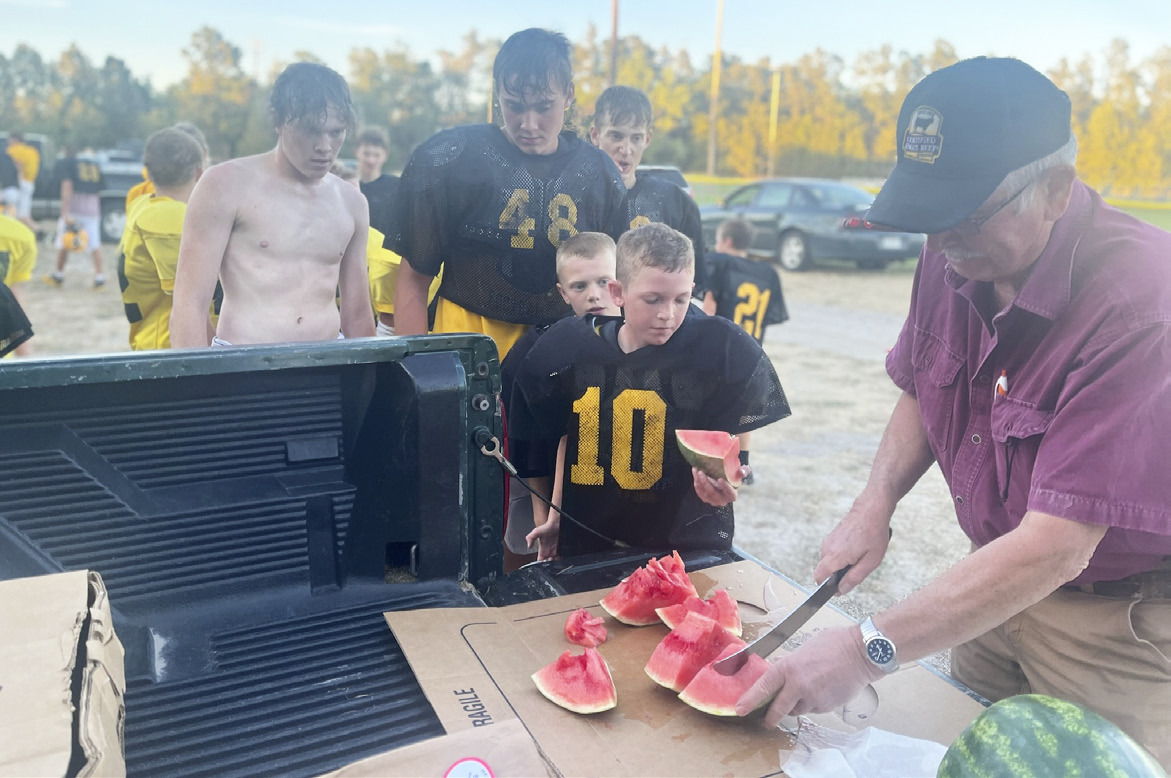 L-r: Ethan Hardin, Tate Kvanvig, Alex Werner, Weston Ourada, Duke Miller and Dick Macke at the football watermelon feed Monday, Sept. 26. Macke’s Grocery has been donating watermelon to the high school football team for over 30 years. This is the second year the youth football teams have also enjoyed it. Gerri Peterson
