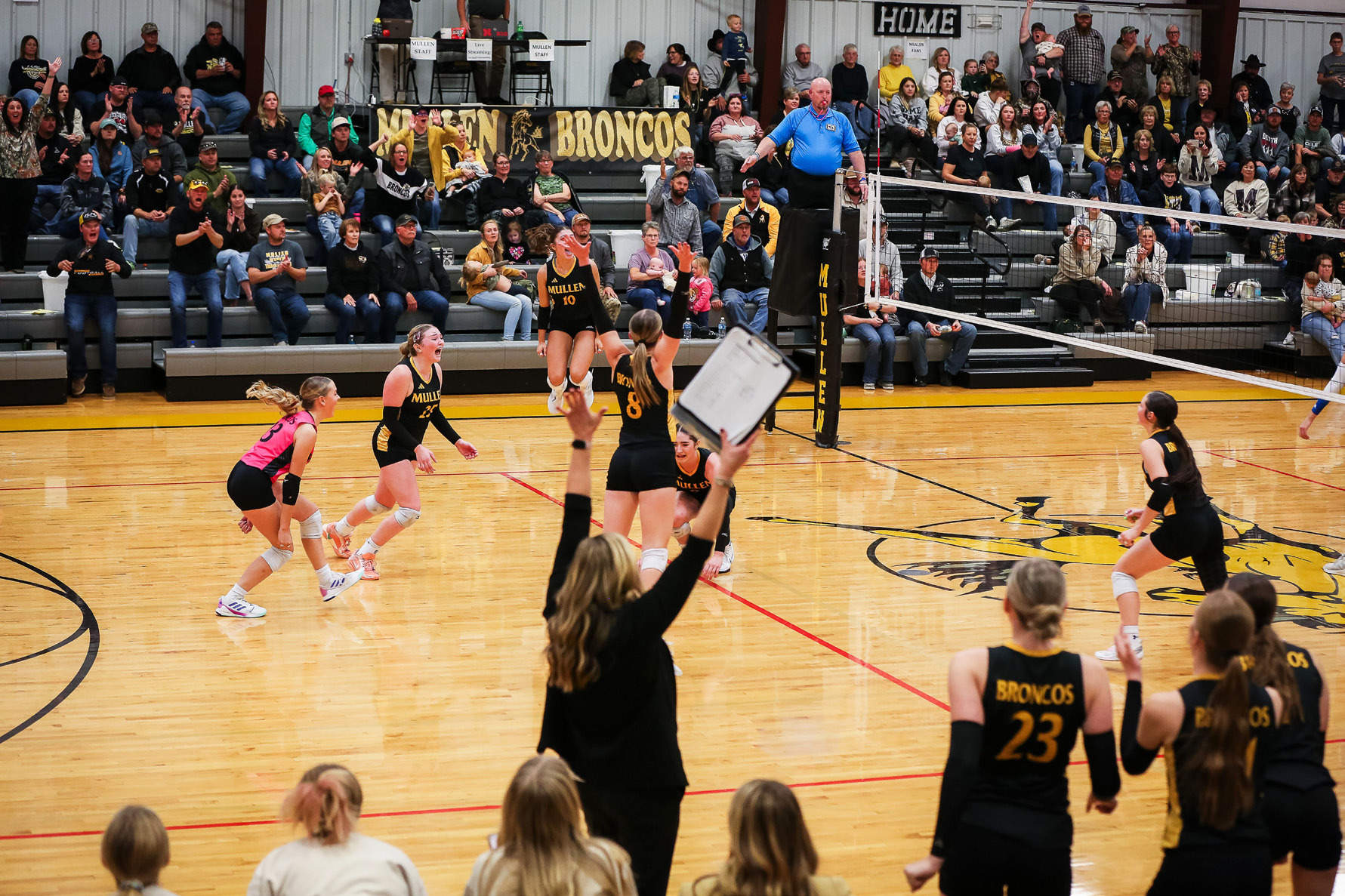 The Lady Broncos on the floor, Head Coach Nichole Ourada and the players on the bench and Mullen fans celebrate as the Broncos clinched their trip to State Volleyball last Saturday afternoon in Mullen. Megan Andersen