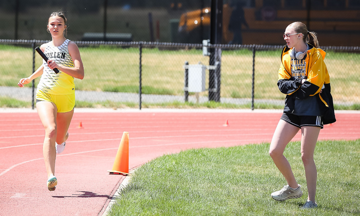 Ady Hampton runs her leg of the 4x8, while teammate Sydnee Cheever cheers her on. Megan Andersen Photography