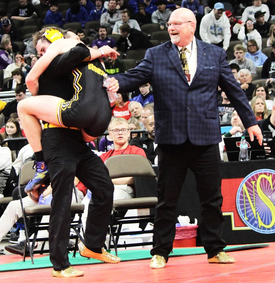 Jason Kraus celebrated winning the Class D 157 wrestling championship by jumping into the arms of his coaches - Bo Pettit (left) and Russ Monette. Kris Forsen