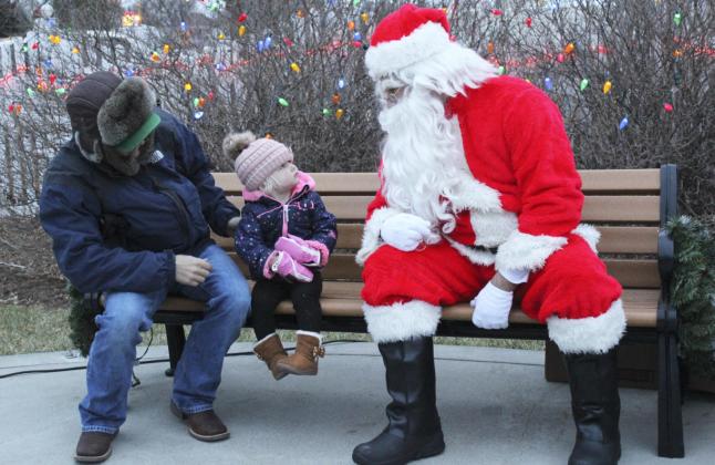 Violet Stichka peered at Santa from underneath her stocking cap last Thursday. She was OK with Santa as long as dad, Michael Stichka, was close by!