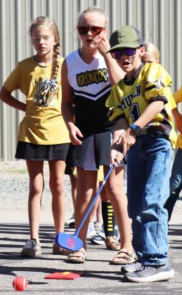 Third grader Trent Cox takes a turn at miniature golf in the all school relay during the Homecoming Pep Rally.