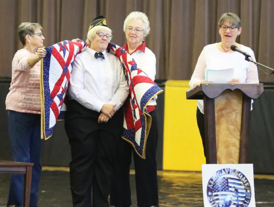 Dawn Mallory receiving her Quilt of Valor from Sue Bonesteel (left) and Doris Starr while Eva Crawford reads.