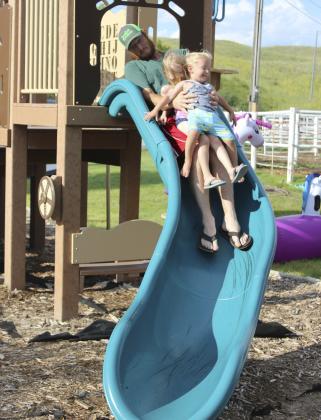 Devan Polt takes both of his kids, Aurora and Arthur, down the fairgrounds slide at the same time during the Redneck Hunger Games’ activities for ages 0-5 last Friday evening. Gerri Peterson