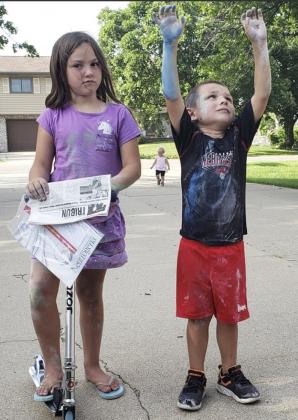 Avery Paitz gets the Tribune from the mail, while brother James shows off his chalk painting in Grand Island in June.