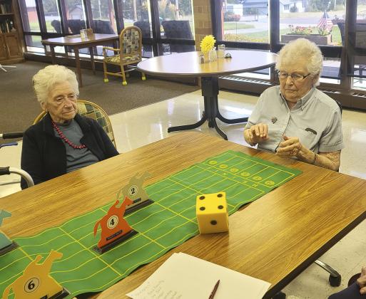Nadene rolling the dice for the horse races, while Wanda watches.