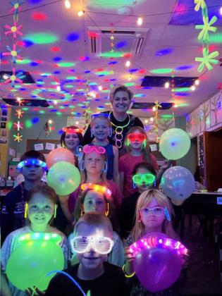 Miss Brown and the 2nd graders on their Glow Day last Thursday. Back row, l-r: Ellie Licking, Fallon Lee, Eve Ericksen. 2nd row: Tru Mundorf, Danielle Peterson, Abigail Gonzalez. Front: Aislynn Connealy, Trent Cox, Dailie Dent, Nora Pohot. courtesy photo