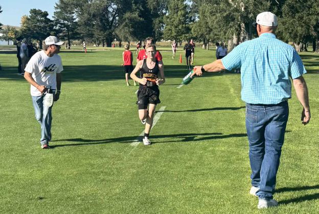 Cross country dads Travis Hampton (left) and Bryan Miller help keep Oakes Miller cool during the Ogallala race last week. Tami Miller