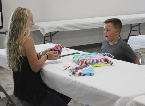 Carson Hegland explains to one of the 4-H judges how he made his tie-dyed items. Gerri Peterson