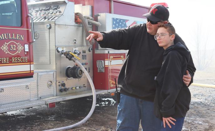Mullen Volunteer Fire Department Fire Chief Tyler Cash was in charge of operating the water truck at Saturday’s training. He’s pictured explaining to his 12-year-old son Cooper Cash what was happening during the training. Cooper said he is counting down the years until he can be-SEE come a volunteer fireman too!