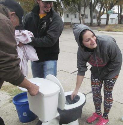 Bill Osborn and Bo Pettit look on while Kelsey Pettit gets enough courage to stick her hand into the toilet filled with homemade “poop” at the Mullen Motor stop. Darlene Osborn