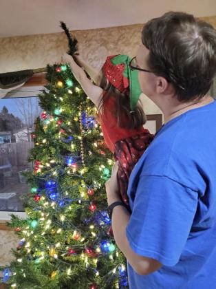 Jim Hessin lifting his daughter Anna to the top of the tree.