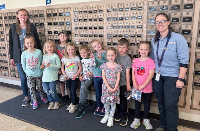 The kindergarten class visited the Mullen Post Office on May 2, where they mailed letters and learned about the mailing process. Pictured l-r: Kindergarten teacher Leanne DeKay, Brogan Jewell, Charlotte Connealy, Kayden Evans, Meyer Vinton, Jaxson Barnes, Anna Ridenour, Aurora Polt, Tate Phillips, Kinley Crisp and Brandi Kearns. Judy Mulligan