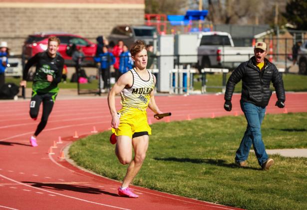 Alex Werner comes around the last corner of his anchor leg of the boys’ champion 4x400 relay with Coach Lance Moore encouraging him in the background. Megan Andersen