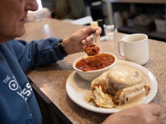 Steve Kuzma, a Lincoln resident and regular diner at Stauffer’s Cafe, tries dipping a bite of cinnamon roll in his bowl of chili. Liz McCue for the Flatwater Free Press