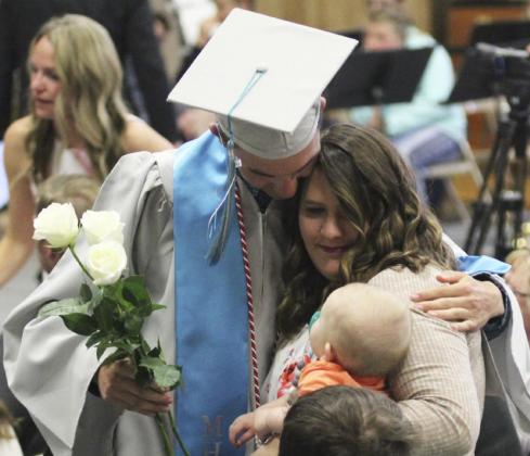 Bryce McIntosh gives his sister-in-law, Brooke McIntosh, and nephew Chasin a hug during the flower presentation last Saturday. Gerri Peterson