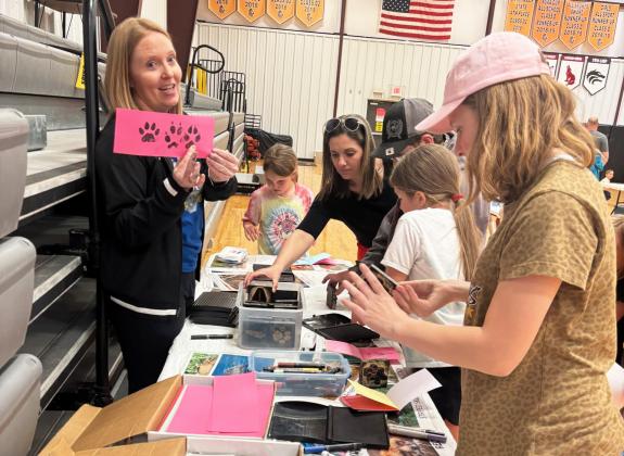 MHS science teacher Sarah Hardin quizzes students on Nebraska wildlife tracks at the station where participants could make wildlife track books with ink stamps. Gerri Peterson