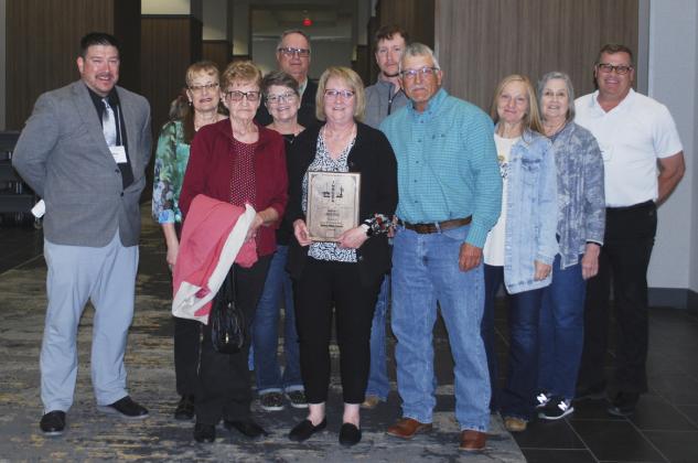 Pam Ginkens with her award last Friday surrounded by friends, family and MPS staff. Pictured l-r: Chris Kuncl, Pam Huddle, Mardell Huddle, Amy and Mark Ewoldt, Pam, Logan and Dale Ginkens, Roxann Brown, Diana Brost and Mike Kvanvig. Jeff Bundy