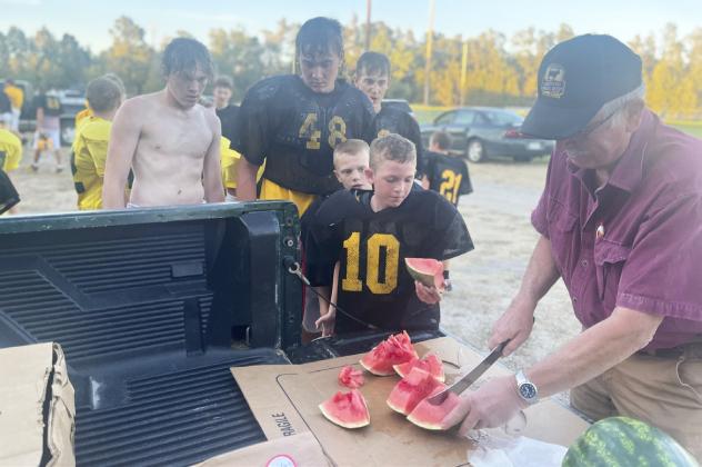 L-r: Ethan Hardin, Tate Kvanvig, Alex Werner, Weston Ourada, Duke Miller and Dick Macke at the football watermelon feed Monday, Sept. 26. Macke’s Grocery has been donating watermelon to the high school football team for over 30 years. This is the second year the youth football teams have also enjoyed it. Gerri Peterson