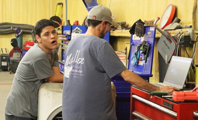 Dana Oliveira checks the computer for his next project in the shop with Matthew.