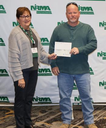 NIRMA Board of Directors member and Morrill County Clerk Kathy Brandt (left), presents a dividend check to Hooker County Sheriff Todd Yost at the program’s annual membership meeting in Kearney on Oct. 24.