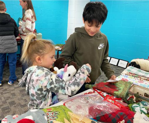 Fifth grader Lorenzo Gonzalez helps kindergartner Doris Boland shop for her family members.