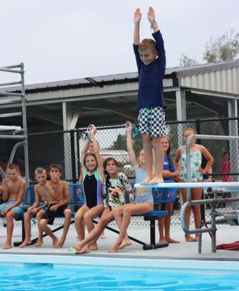 After some coaching on technique from his big sisters and their friends behind him, Brogan Seeley prepares to step off the low board in the smallest splash competition.