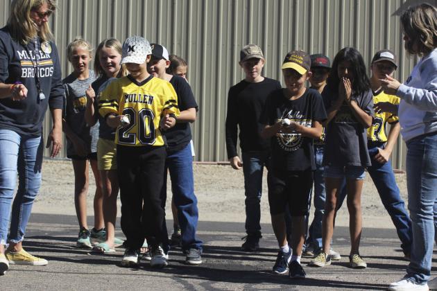 3rd grader Tuff Pettit (left) and 4th grader Jaxyn Evans start the egg race during the Homecoming pep rally games for their classes.