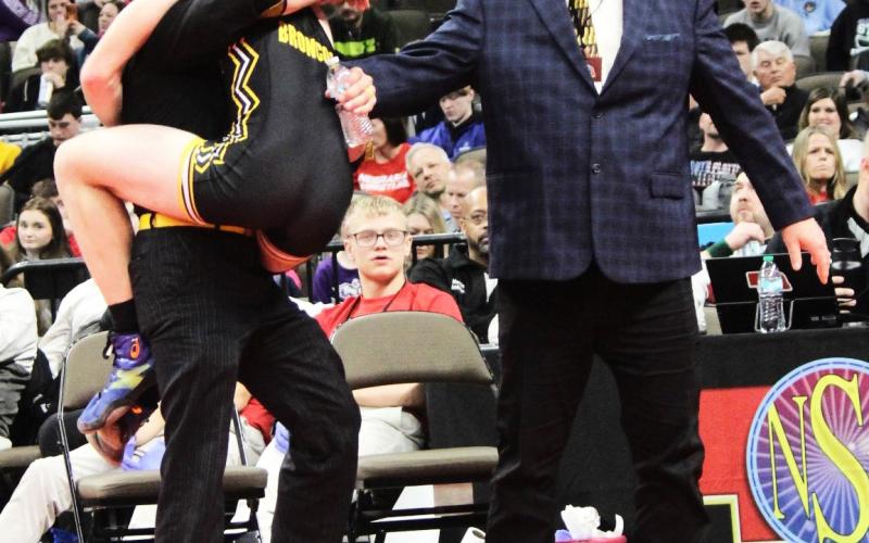 Jason Kraus celebrated winning the Class D 157 wrestling championship by jumping into the arms of his coaches - Bo Pettit (left) and Russ Monette. Kris Forsen