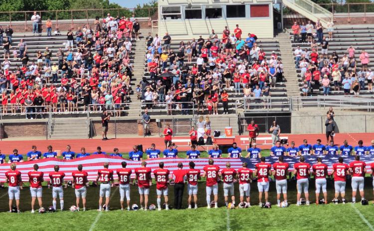 The West and East teams held the flag during the national anthem prior to kickoff of their All-Star Game. Mullen’s Justin French is #32 with his back to the camera in the middle right of the photo. Larry French is also in the photo, fourth from the top left of the flag. Christie Jones