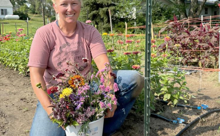 Justa Deibler with a bucket full of her flowers she snipped at the lot last Thursday morning. Gerri Peterson