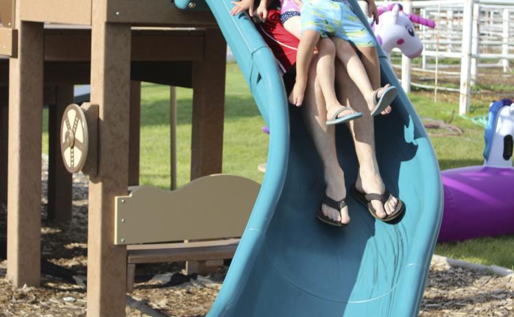 Devan Polt takes both of his kids, Aurora and Arthur, down the fairgrounds slide at the same time during the Redneck Hunger Games’ activities for ages 0-5 last Friday evening. Gerri Peterson