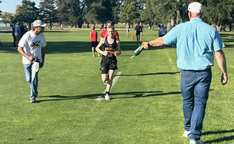 Cross country dads Travis Hampton (left) and Bryan Miller help keep Oakes Miller cool during the Ogallala race last week. Tami Miller