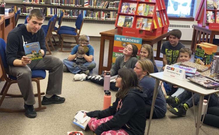 Senior Brendon Walker reads to the fifth graders during the Scholastic Book Fair in the high school library last month. courtesy photo