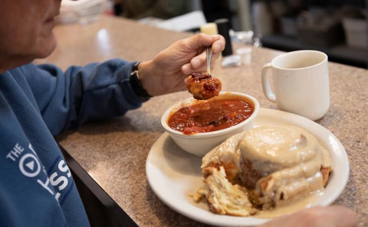 Steve Kuzma, a Lincoln resident and regular diner at Stauffer’s Cafe, tries dipping a bite of cinnamon roll in his bowl of chili. Liz McCue for the Flatwater Free Press