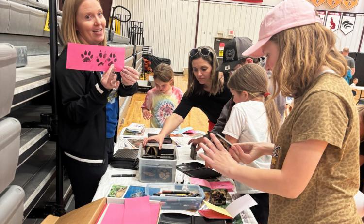 MHS science teacher Sarah Hardin quizzes students on Nebraska wildlife tracks at the station where participants could make wildlife track books with ink stamps. Gerri Peterson