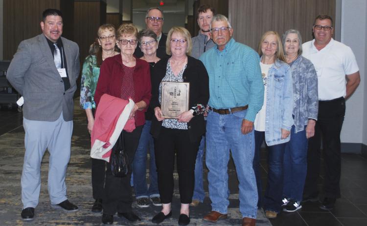Pam Ginkens with her award last Friday surrounded by friends, family and MPS staff. Pictured l-r: Chris Kuncl, Pam Huddle, Mardell Huddle, Amy and Mark Ewoldt, Pam, Logan and Dale Ginkens, Roxann Brown, Diana Brost and Mike Kvanvig. Jeff Bundy