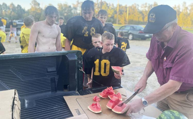 L-r: Ethan Hardin, Tate Kvanvig, Alex Werner, Weston Ourada, Duke Miller and Dick Macke at the football watermelon feed Monday, Sept. 26. Macke’s Grocery has been donating watermelon to the high school football team for over 30 years. This is the second year the youth football teams have also enjoyed it. Gerri Peterson