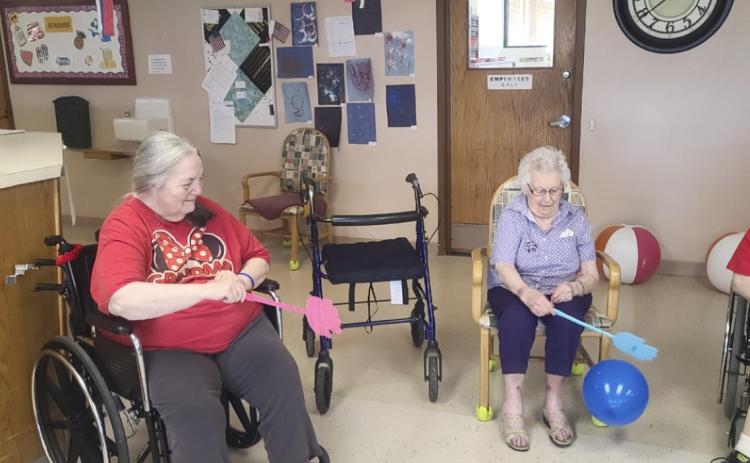 Ann Connel (left) and Nadene Andersen playing fly swatter balloon volleyball.