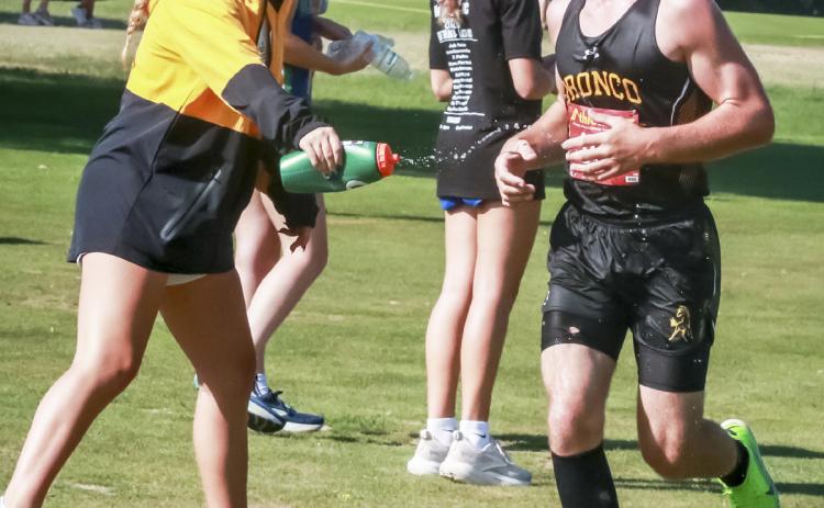Hunter Brown gets a squirt of water for a cool down and words of encouragement from teammate Riley Hegland last week. Carolee Brown Photography