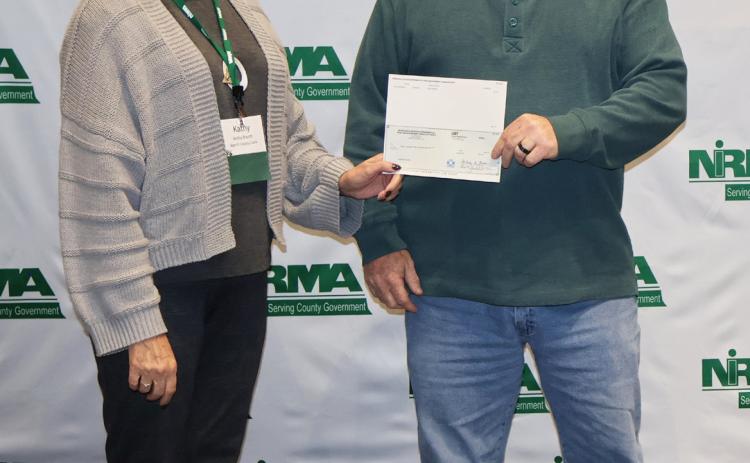 NIRMA Board of Directors member and Morrill County Clerk Kathy Brandt (left), presents a dividend check to Hooker County Sheriff Todd Yost at the program’s annual membership meeting in Kearney on Oct. 24.