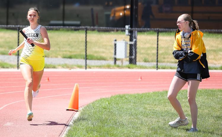 Ady Hampton runs her leg of the 4x8, while teammate Sydnee Cheever cheers her on. Megan Andersen Photography